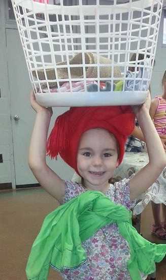 Practicing carrying items in a basket on her head with a baby on her back -- similar to what many Western African girls and women do