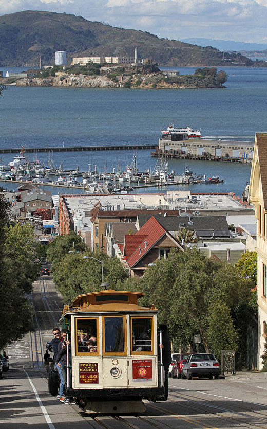 One of San Francisco's cable cars along with a view of Alcatraz in the bay