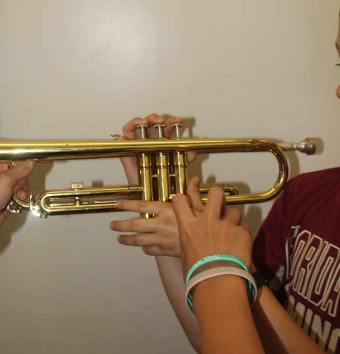 One of the older students showing how to hold and play a trumpet