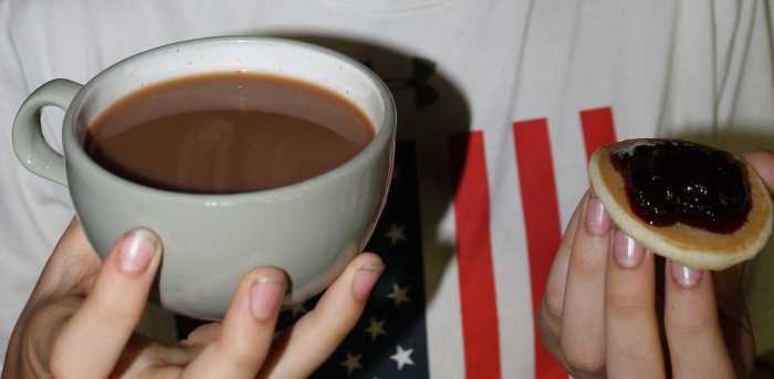 Tea with milk and sugar and pikelets with jam