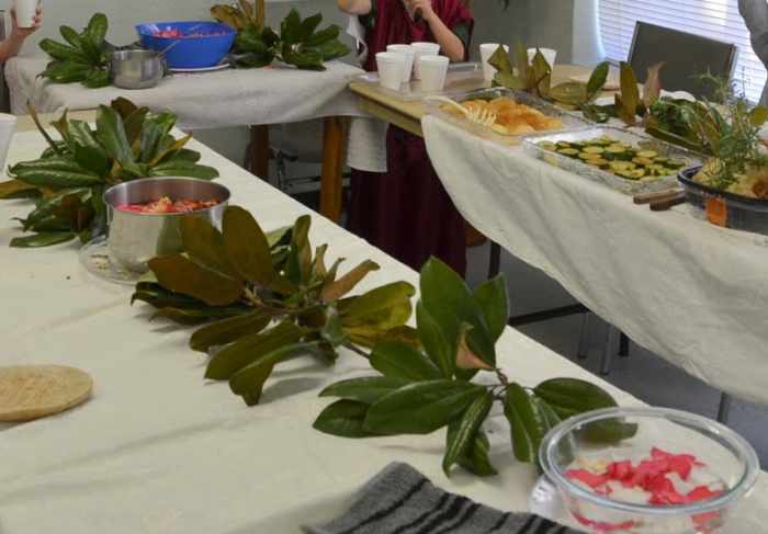 Setting up 3 tables in a U-shape with white tablecloths and greenery - Add bowls of water with flower petals for the "aquamaniles."